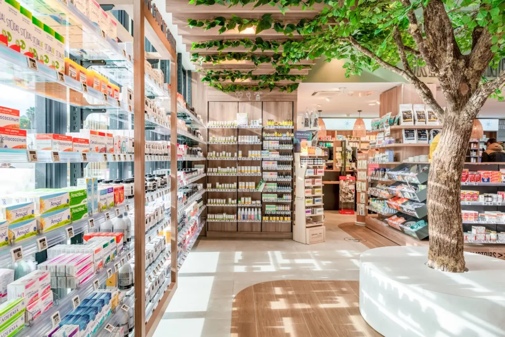 Pharmacie agencée par Cubik, avec un arbre au cœur de l’espace de vente.