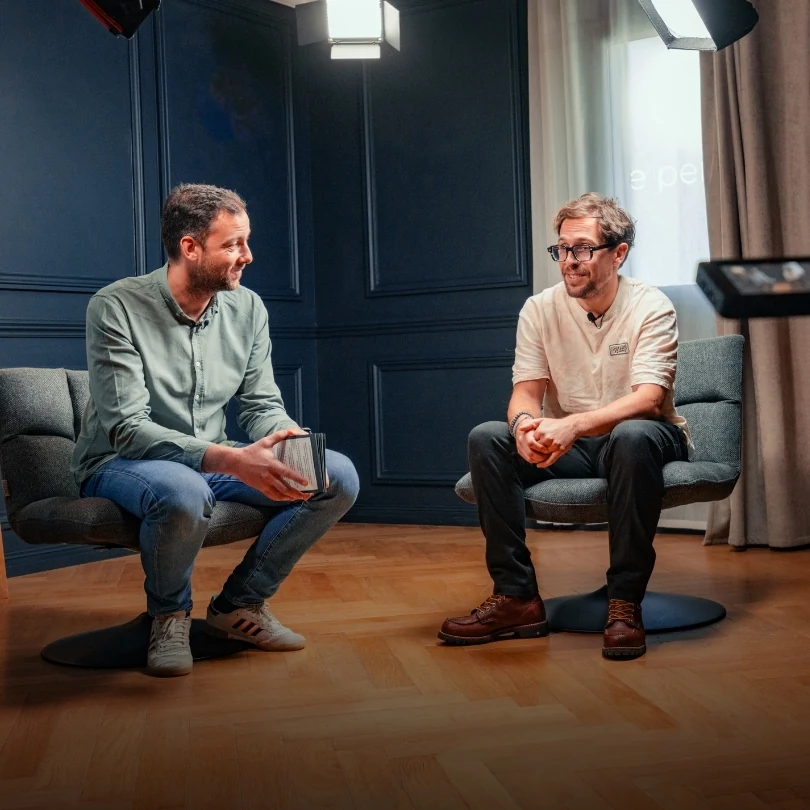 Tournage du podcast Cubik : deux intervenants en fauteuil dans un studio bleu nuit.