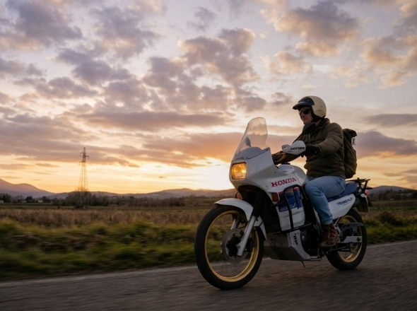 Un motard sur une moto trail au coucher du soleil, sur une route de campagne
